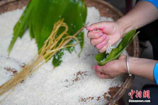 资料图：2019年6月6日，贵州黎平县三龙侗寨，侗族妇女包棕子迎接端午节。在当地，端午时节，侗族妇女采摘竹叶包粽子迎端午节，庆祝“关秧门”。/p中新社记者 贺俊怡 摄